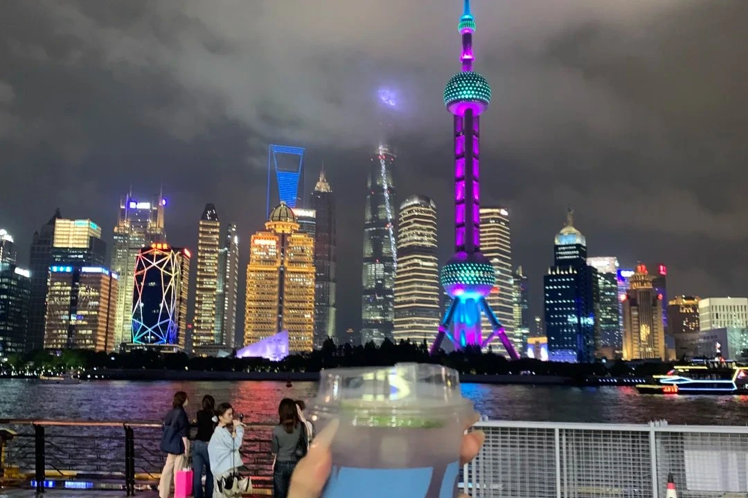 The Bund promenade along the Huangpu River at night with colonial buildings and Lujiazui skyline across the water
