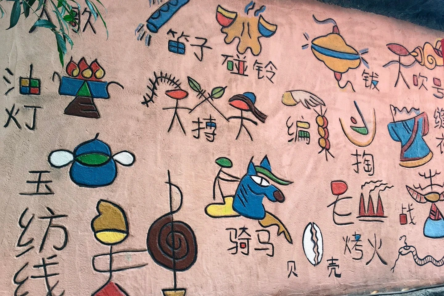Colorful Dongba pictographic characters painted on a stone wall in Lijiang showing Naxi sacred symbols