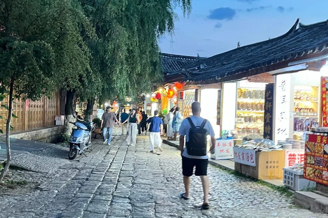 Cobblestone street in Lijiang Old Town at twilight with willow trees and lanterns