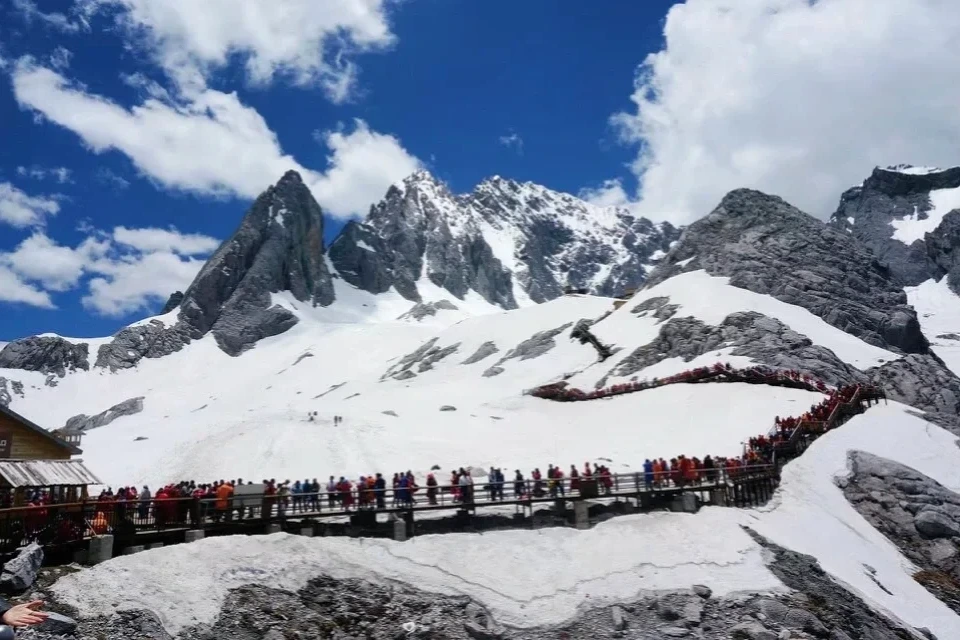 Tourists on the elevated walkway at Jade Dragon Snow Mountain with snow fields around them