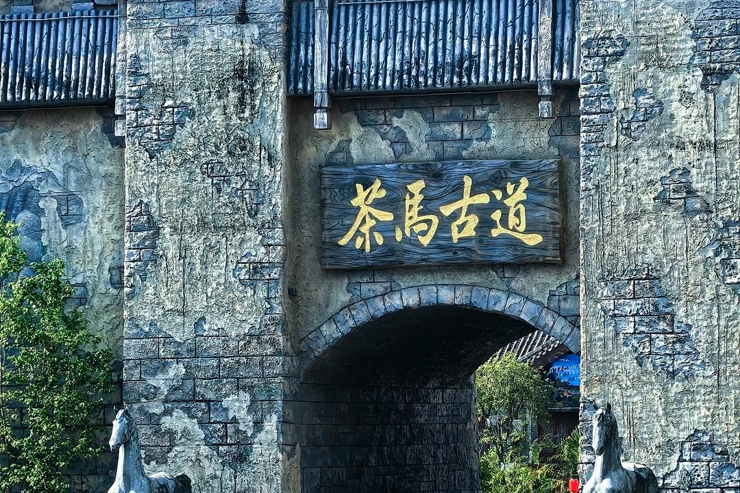 Tea Horse Road old stone gateway with wooden Tea Horse Road plaque and bronze horse sculptures