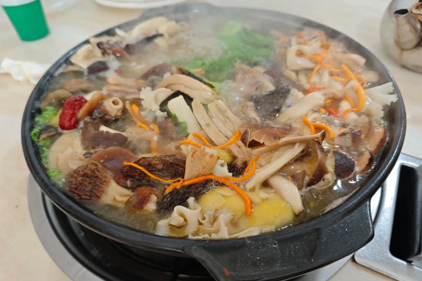 Lijiang wild mushroom hot pot with various wild mushrooms and herbs in copper pot on table