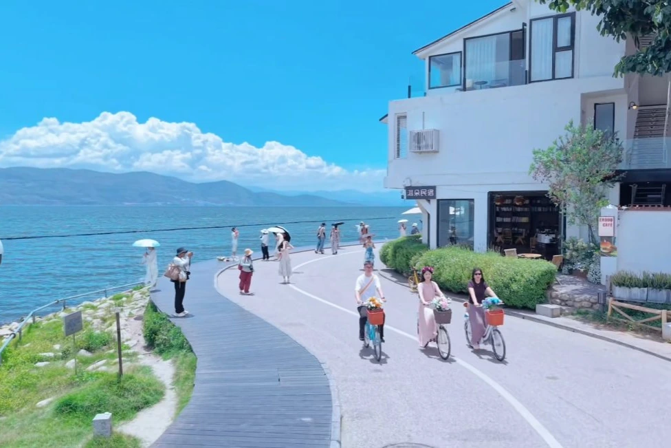 Cyclists riding along Erhai Lake's blue ecological corridor with Cangshan mountains in the distance