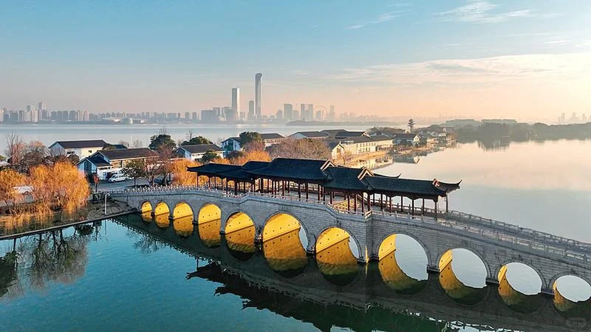 Suzhou skyline with ancient arched canal bridge and white-walled houses at golden hour